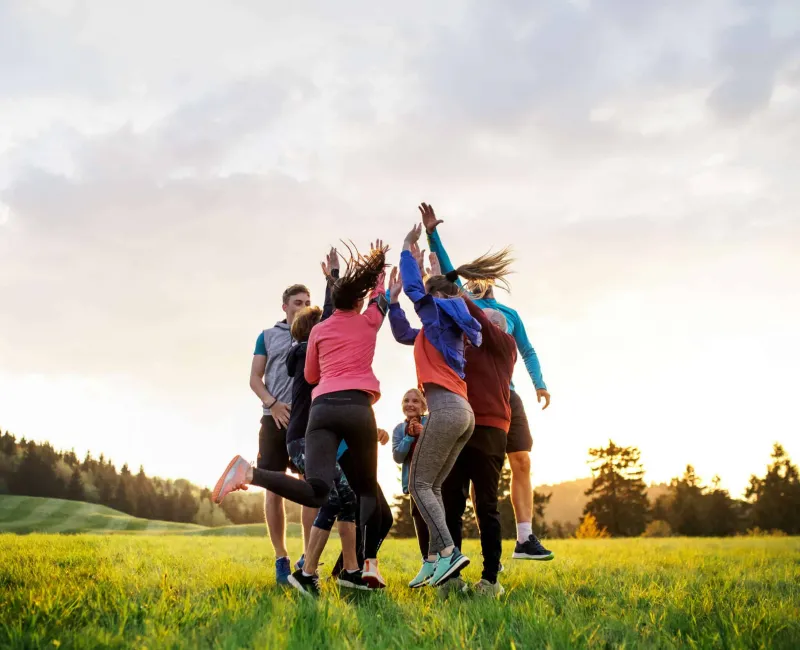 Large group of fit and active people jumping after doing exercise in nature