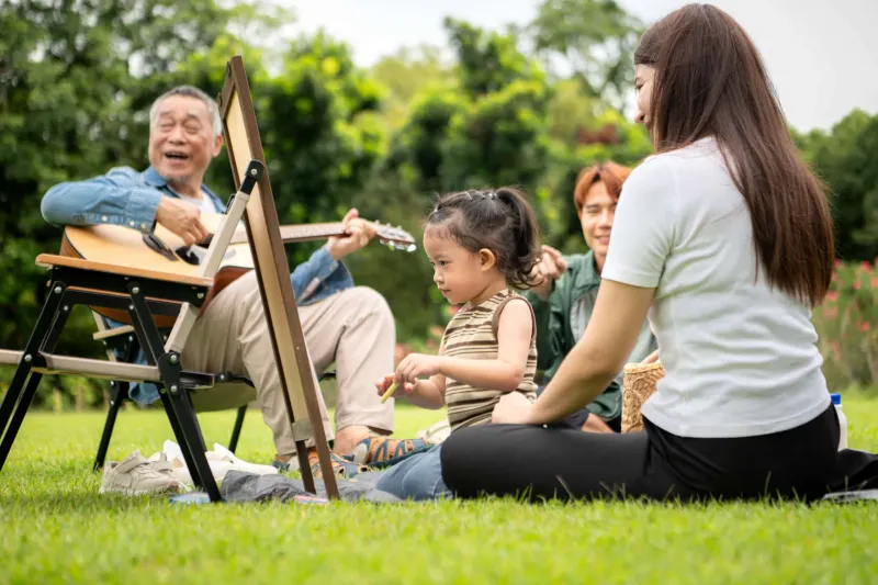 Happy multi generational Asian family enjoying picnic in the par