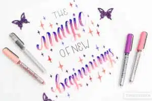 the-magic-of-new-beginnings - Webinare und Kurse Handlettering-Kunstwerk auf weißem Papier mit dem Schriftzug „The magic of new beginnings" in einem Farbverlauf von Rosa über Orange bis Lila im Brushlettering-Stil, umgeben von Sternchen. Daneben Brushmarker Pro Stifte in Rosa, Lila und Silber sowie dekorative lila Schmetterlinge aus Papier. Foto: Timo Ostrich.